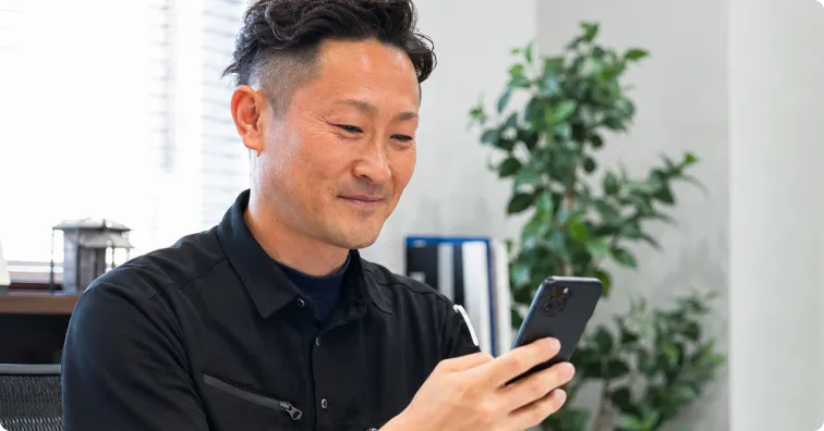 スマートフォンでLINEの連絡を確認する担当者